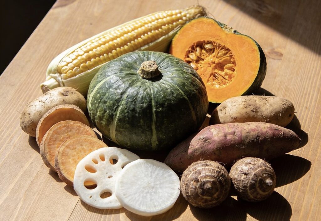 テーブルの上にかぼちゃ、蓮根、さつまいも、とうもろこし、里芋、じゃがいもが並ぶ